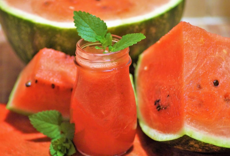 watermelon drink next to watermelon slices on table as a burger side dish